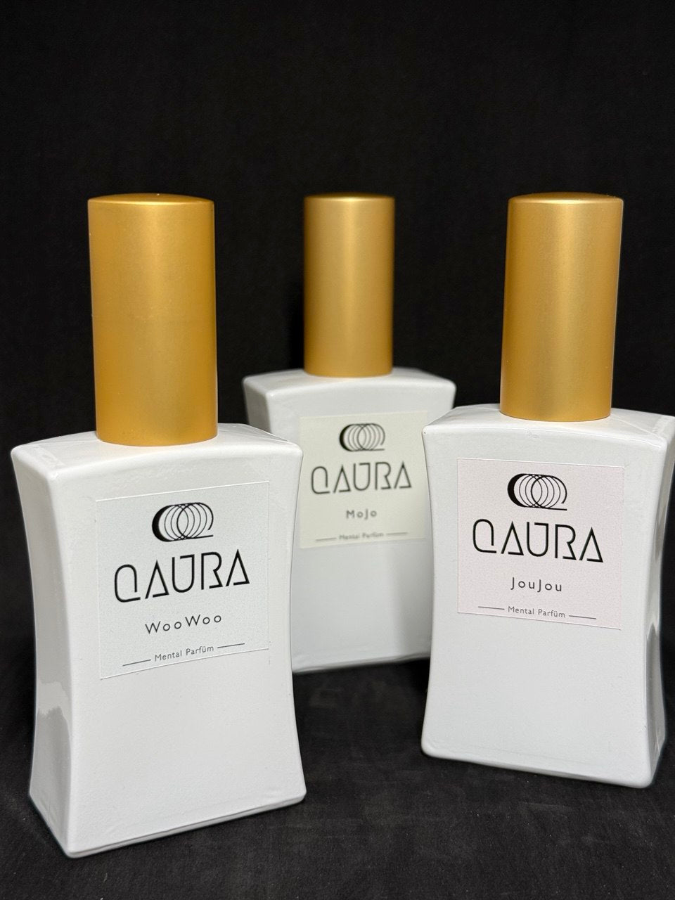QAURA Mental Parfuems WooWoo, MoJo, JouJou stehen nebeneinander auf einem Holz-Untergrund.