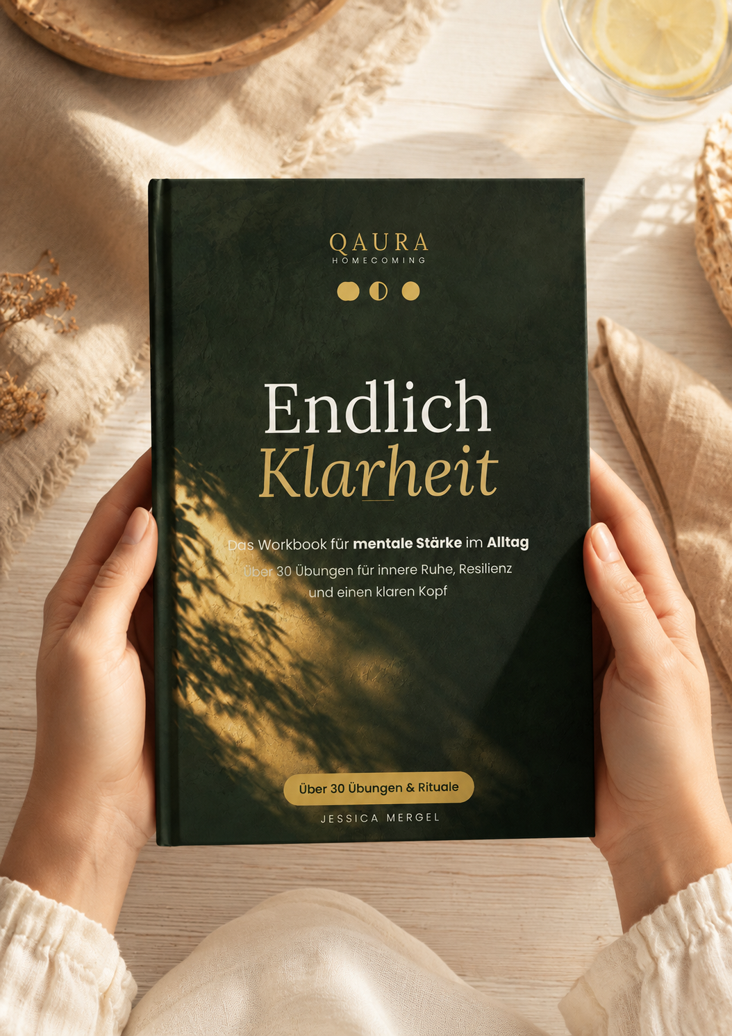 Cover des QAURA Workbooks „Endlich Klarheit“ in Dunkelgrün, in den Händen gehalten